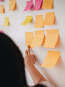 A woman points at several post-it notes on a wall