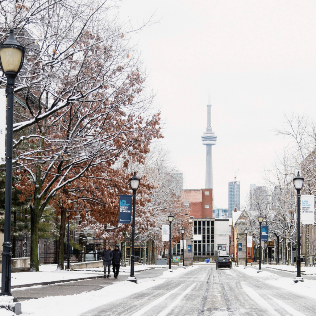 A snowy road leading out of the UTSG campus - the CN Tower in the background.