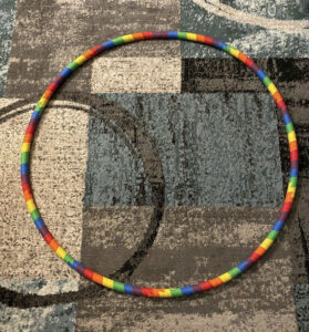 A rainbow-coloured pride hula hoop on the ground. 